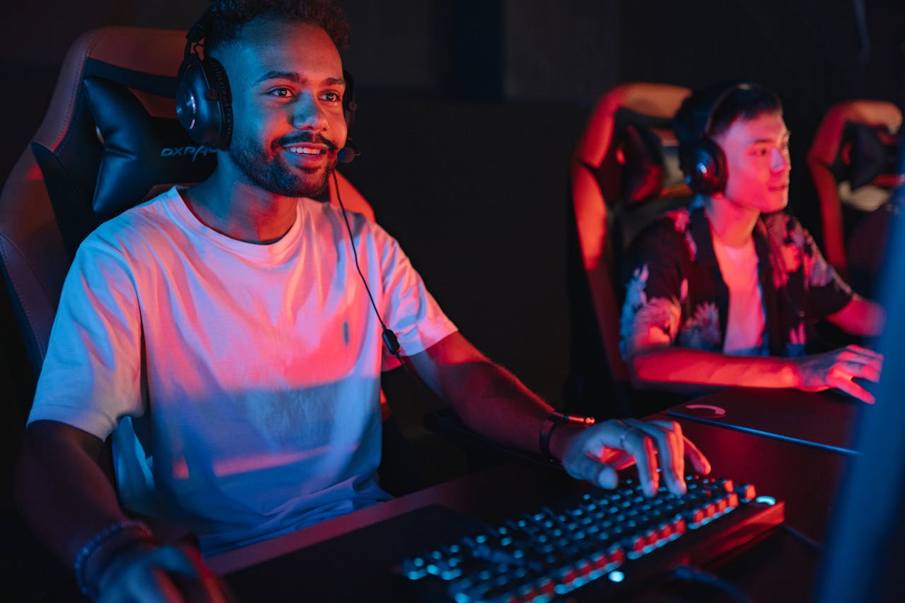 Two male gamers intensely focused during a gaming session in a cybercafe with colorful lighting.